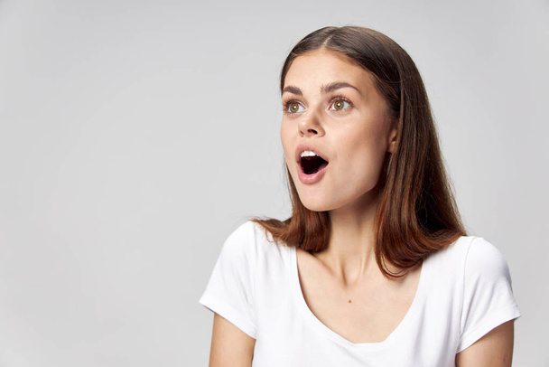 Femme surprise avec bouche ouverte regarde sur le côté blanc T-shirt  - Photo, image