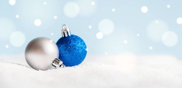 Christmas balls on surface with snow and defocused lights with copy space. - Foto, afbeelding