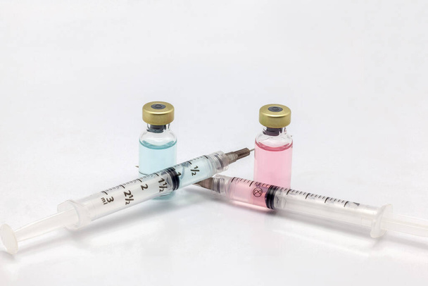 Дві різні ізольовані скляні пляшки вакцини з різними кольоровими рідинами та двома кольоровими рідкими шприцами
 - Фото, зображення
