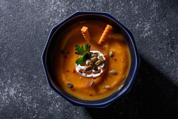 pumpkin cream soup in blue plate on grey background, seasonal autumn dish concept, top view - Photo, Image