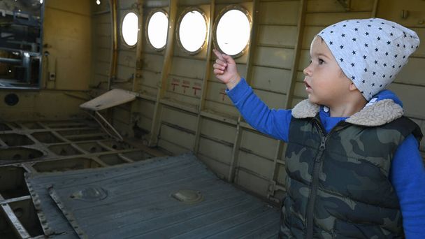 Ένα παιδί μέσα σε ένα εγκαταλελειμμένο αεροπλάνο. Υψηλής ποιότητας φωτογραφία - Φωτογραφία, εικόνα