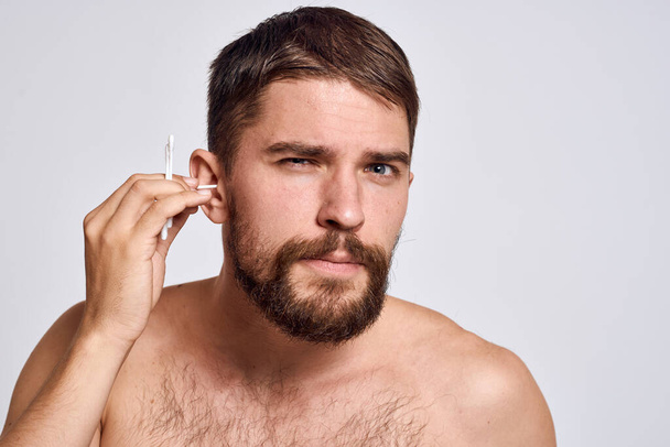 Hombre barbudo con hombros desnudos hisopos de algodón higiene cuidado corporal - Foto, Imagen