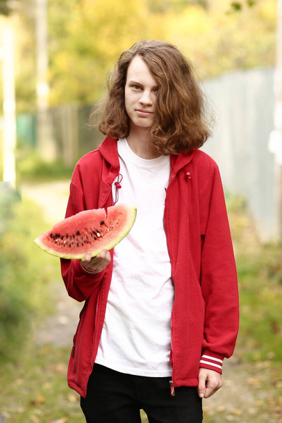 nastolatek chłopiec z wody melon plasterek zbliżyć zdjęcie na jesień tło - Zdjęcie, obraz