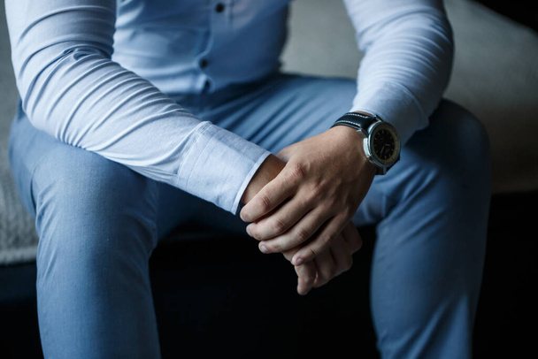 A man elegant businessman buttons a watch on his hand he is dressed in a white dress shirt - Foto, Imagen