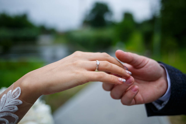 Mãos femininas doces da noiva com um anel de casamento dourado no dedo anelar - Foto, Imagem