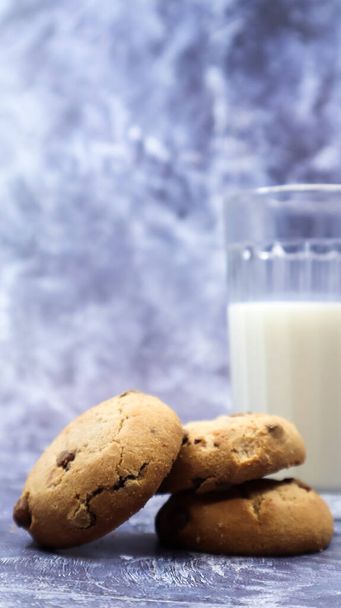 American gluten free chocolate chip cookies with glass glass of vegetable milk on gray background. Chocolate chip cookies. Sweet pastries, dessert. Culinary background. Vertical photography - Photo, Image