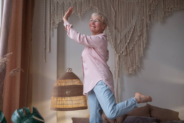 Mature carefree woman at morning jumping on the bed having fun - Fotoğraf, Görsel