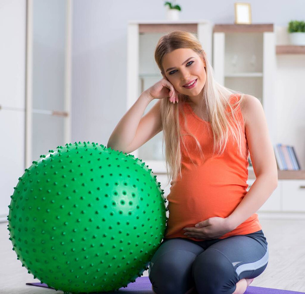Young woman preparing for birth exercising at home - 写真・画像