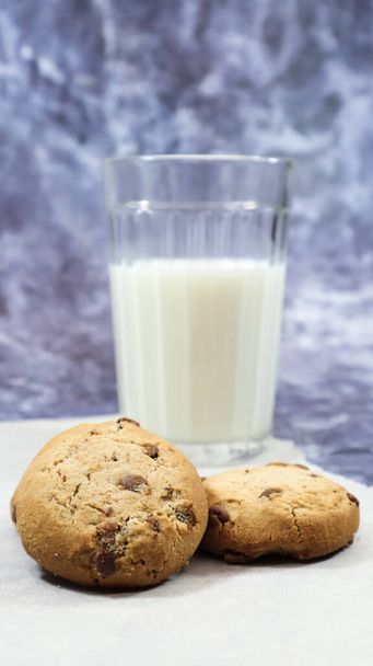 American gluten free chocolate chip cookies with glass glass of vegetable milk on gray background. Chocolate chip cookies. Sweet pastries, dessert. Culinary background. Vertical photography - Photo, Image