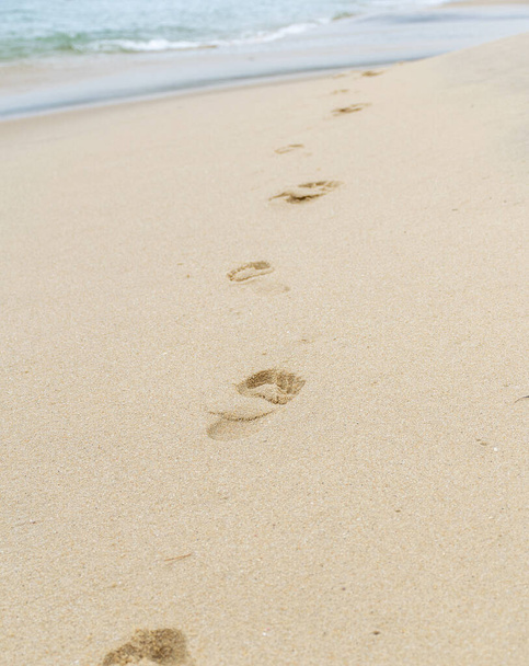 Ślady stóp człowieka na piasku plaży (morze w tle)). - Zdjęcie, obraz