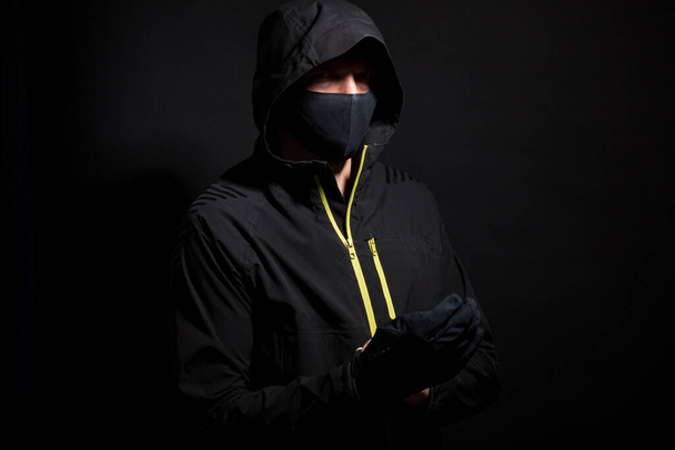 Portrait d'homme invisible hacker dans le capot isolé sur fond noir. - Photo, image