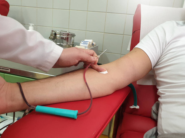 Dawca krwi siedzący na krześle medycznym podczas oddawania krwi. Koncepcja krwiodawstwa. Koncepcja ratowania życia - Zdjęcie, obraz