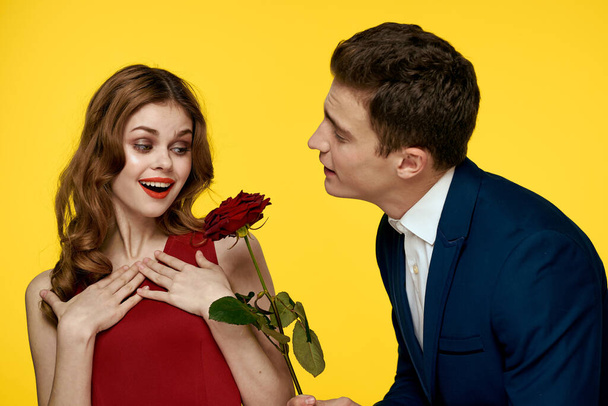 Young charming couple rose relationship romance gift as a lifestyle yellow isolated background - Fotó, kép