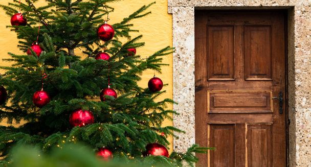 Heiligabend Feiertage Zeit geschmückter Baum in der Nähe Holztür Eingang Fassade Objekt Hintergrund Außenansicht - Foto, Bild