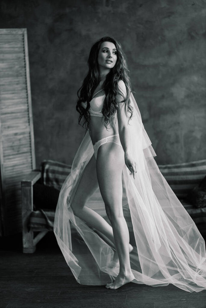 Portret van een mooie jonge vrouw in een wit ondergoed. Morgen van de bruid. - Foto, afbeelding