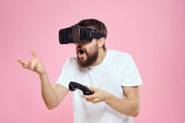 Man in virtual reality glasses joystick παίζοντας video lifestyle λευκό t-shirt ροζ φόντο - Φωτογραφία, εικόνα