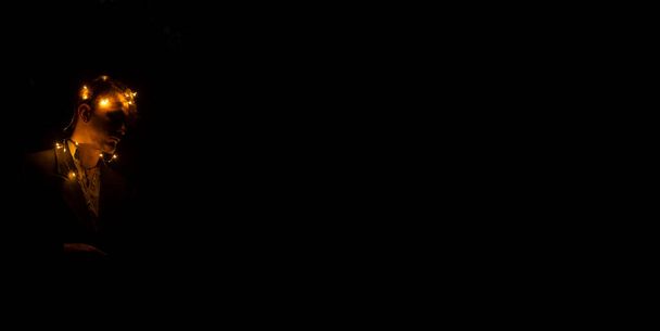 Мягкая концепция фокус человек портрет лицо с гирляндой лампы на голове панорамный черный простой фон пространство для копирования или текст здесь - Фото, изображение
