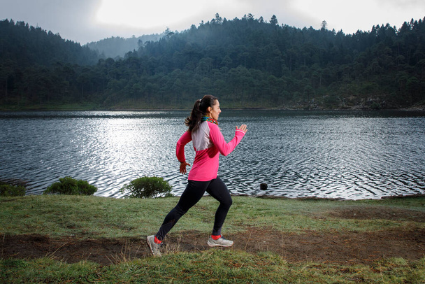 Atleta correndo ao ar livre perto de um lago com montanhas no fundo - Foto, Imagem