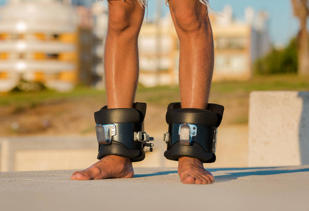 Man in anti zwaartekracht of inversie laarzen voor ondersteboven opknoping. Sportuitrusting. Laarzen helpen om rugpijn, spierspanning en krampen te verminderen. Helpt bij het strekken van de nek, schouderspieren en rug.  - Foto, afbeelding