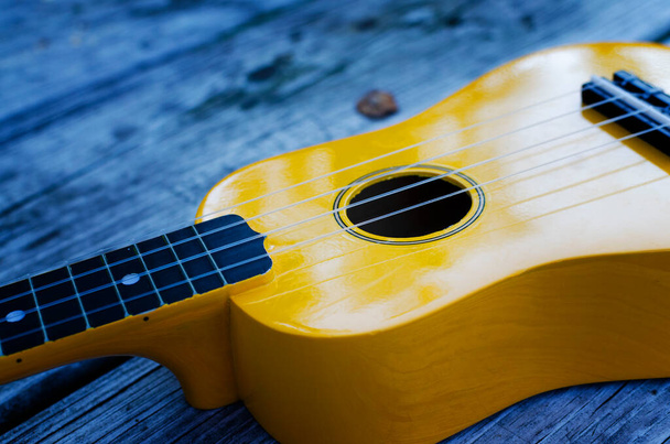 Gele Ukulele muziekinstrument buiten op tafel met blure effect - Foto, afbeelding