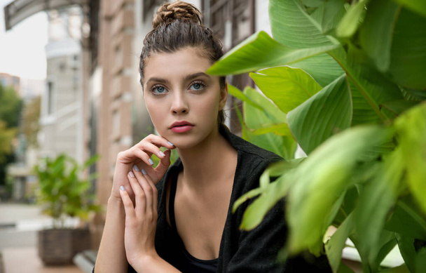 Portrait of young pretty student woman sitting at the city openspace. Beauty model with natural make up and long eyelashes smiles outdoor. Copyspace. - Foto, imagen
