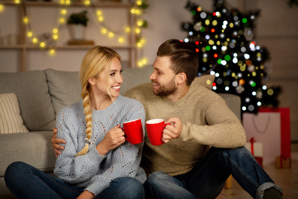 Эмоциональная рождественская пара, обнимающая и пьющая какао - Фото, изображение