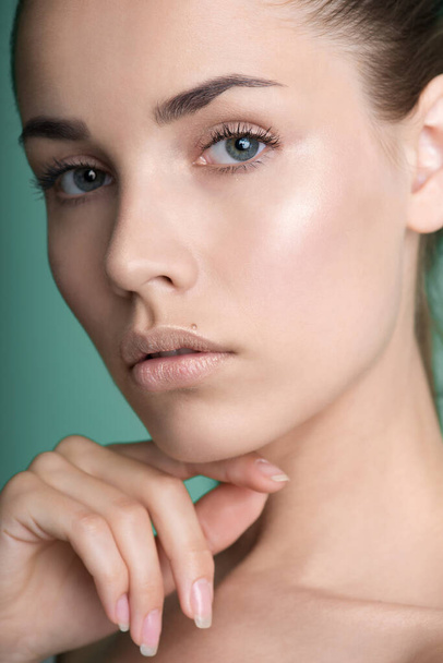 Close up of  beauty model face with natural nude make up and and hand with manicure touching face. Spa, skincare and wellness. Beautiful young woman with clean perfect skin. Closeup, background, copyspace. - Valokuva, kuva