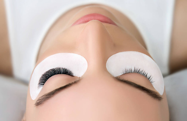 Eyelash Extension Procedure.  Beauty Model with  Perfect Fresh Skin and Long Eyelashes. Slincare, Spa and Wellness. Make up,  Hair and Lashes. Close up. - Photo, image