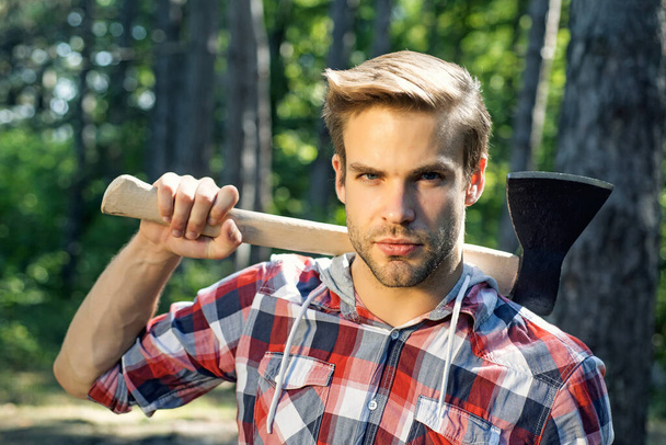 Lumberjack on serious face carries axe on shoulder. - Photo, image