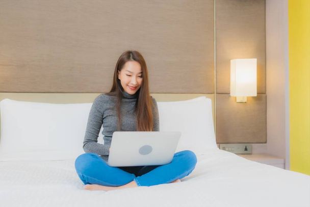 Muotokuva kaunis nuori aasialainen nainen käyttää tietokonetta kannettava sängyllä makuuhuoneessa sisustus - Valokuva, kuva