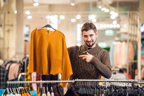 A young man choosing clothes for his girlfriend in a shop - Fotoğraf, Görsel
