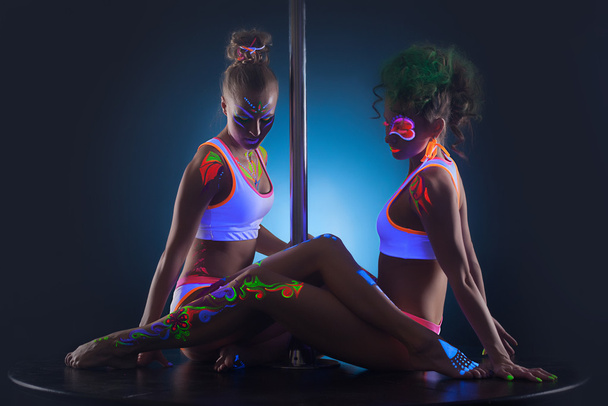 Two modern pole dancers with UV makeup - Foto, imagen
