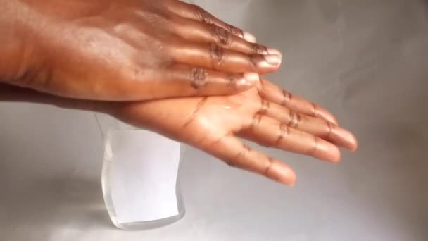 Τα χέρια μιας νεαρής, μαύρης, αφρικανής κυρίας χρησιμοποιούν, χρησιμοποιώντας υλικό απολύμανσης χεριών. Πιέστε από το βίντεο κλιπ μπουκάλι. Τρίβει τα χέρια της για να απολυμάνει και ανάμεσα στα δάχτυλα. Υγιεινή, Coronavirus, έννοια Covid-19. Ποικιλότητα. Εθνικότητα. - Πλάνα, βίντεο
