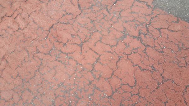 Estrada danificada de cor vermelha ou caminho pavimentado com crepitações de diferentes shpaes. Textura rachada com espaço de cópia para texto e mensagens - Foto, Imagem