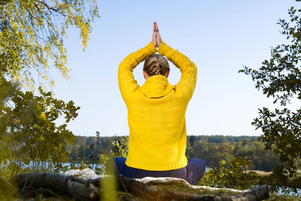 Красивая молодая девушка медитирует в осеннем парке. женщина медитирует в лесу в солнечный день - Фото, изображение