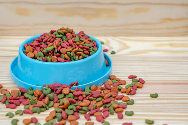Чаша для домашних животных с сухой пищей на деревянном столе - Фото, изображение