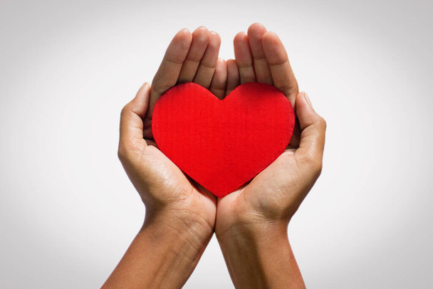 ένας άνθρωπος που κρατά κόκκινη καρδιά σχήμα περικοπή board.heart care.world ημέρα της καρδιάς. - Φωτογραφία, εικόνα