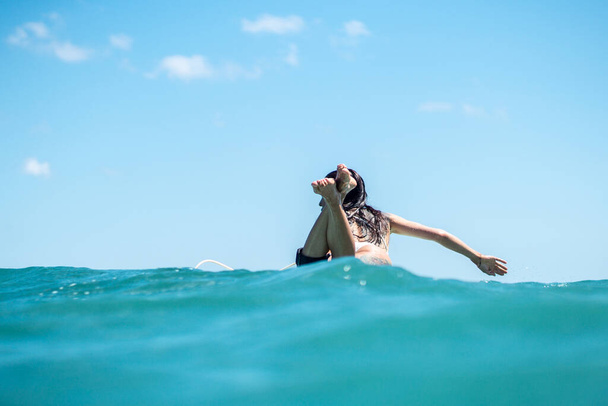 Portrait of surfer girl on surf board in blue ocean pictured from the water in Bali - Φωτογραφία, εικόνα