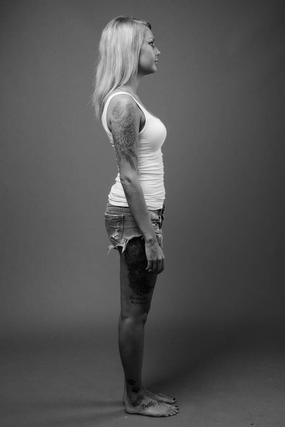 Студийный снимок молодой красивой скандинавской женщины с светлыми волосами на сером фоне в черно-белом - Фото, изображение