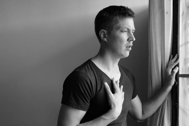 Портрет молодого красивого чоловіка з астматичним нападом вдома в чорно-білому
 - Фото, зображення