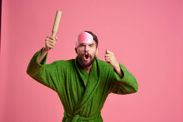 Портрет человека в розовой маске для сна и модель раздражительности зеленого халата - Фото, изображение