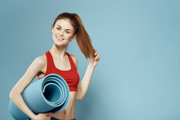Mujer deportiva en camiseta roja para ejercicios de entrenamiento estilo de vida fondo azul - Foto, imagen