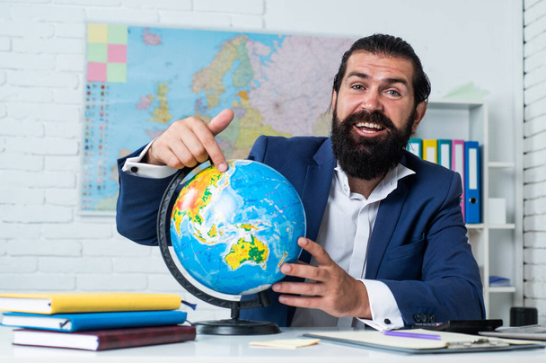 geography studying. informal education. male student sit in school classroom with map. pass the exam. learning the subject. geographer. happy man with beard pointing at globe - Fotografie, Obrázek
