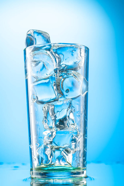 pieces of pure real ice in a glass on a colored gradient background, cubes are rounded - Photo, Image