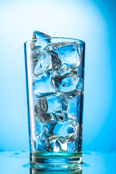 pieces of pure real ice in a glass on a colored gradient background, cubes are rounded - Fotó, kép
