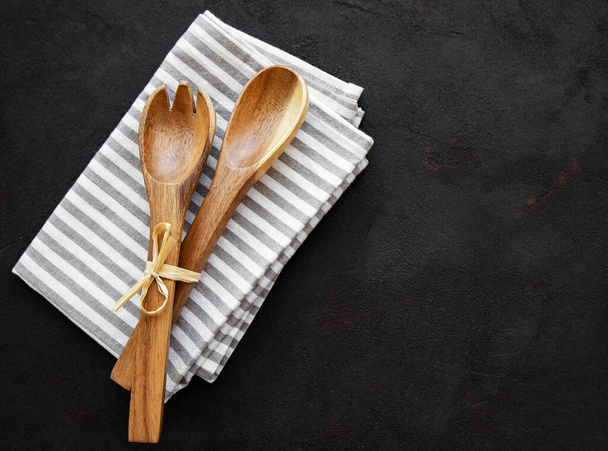 Two wooden salad spoons  and napkin on a black background, flat lay - Photo, Image