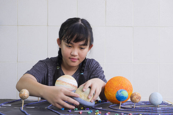 Selective focus at young Asian girl making homemade solar system model on wooden table at home for her science home project at school - Photo, Image