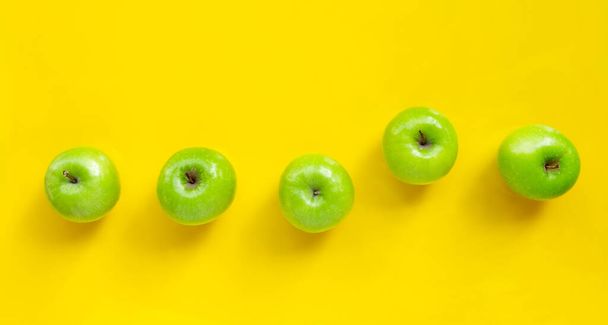 Green apples on yellow background. Copy space - Фото, зображення