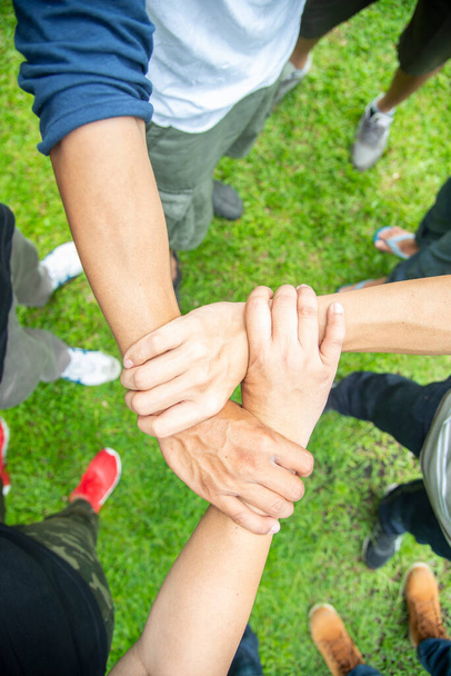 Solidaarisuus yhdistää ihmiset, jotka tekevät yhteisöllistä yhteistyötä. Henkiryhmän kädet työskentelevät yhdessä ulkona. Yhtenäisyys vahva kädenpuristus ihmisten kanssa tai sopimus tunne tai onnellinen monipuolinen koulutus toiminta - Valokuva, kuva