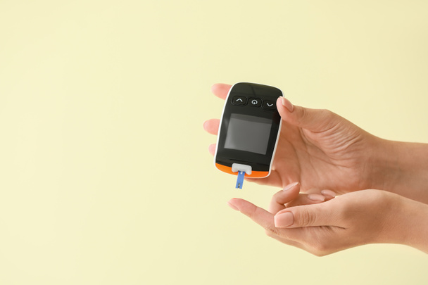 Female hands with glucometer on color background. Diabetes concept - Photo, Image